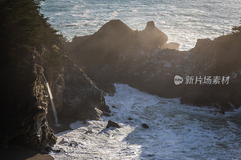 雄伟的瀑布在日落大Sur - Rocks和海洋美丽的阳光自然背景